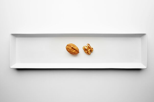 营养胡桃木的封闭和开放隔离在长方形陶瓷板的中间 放在白色的桌子上外壳仁开放