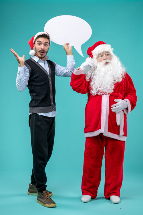 成人前视图圣诞老人和年轻的男性谁持有蓝色背景上的白色标志圣诞老人白色微笑