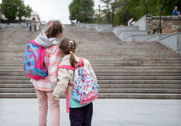 童年两个背着背包的小女孩手牵手一起上学童年的友谊友谊学校台阶