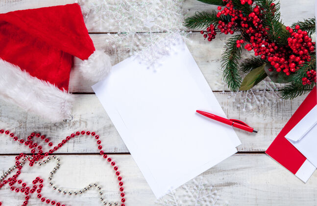 礼物纸上的空白纸上有一支钢笔和圣诞装饰品礼物 圣诞老人 桌子 庆典 信件 信封 钢笔 礼物 帽子 书写 信息 木制 传统 乡村 书写 临期 床单 空白 乡村 愿望 空 颠簸