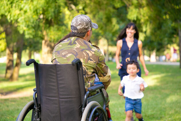 军队两个快乐的孩子和他们的妈妈跑向残疾的退役军人父亲 拥抱他退伍军人或回家的概念爸爸团结会议