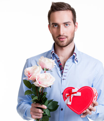 浪漫一个年轻英俊的男人 带着一朵粉红的玫瑰和一份礼物——与世隔绝的白色鞠躬严肃惊喜