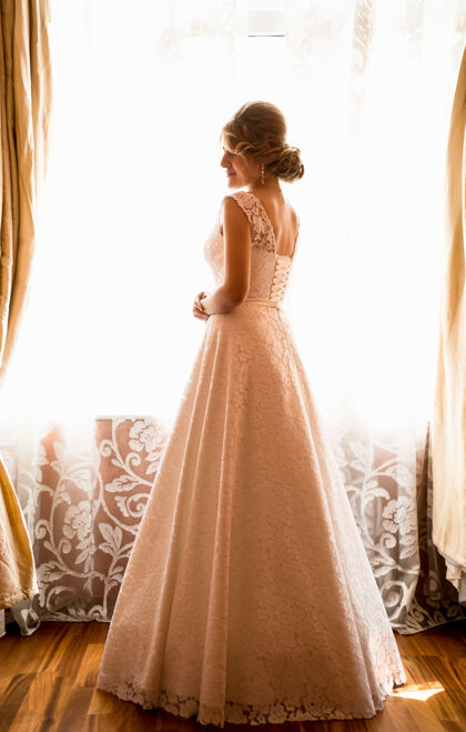 女士优雅新娘在酒店房间橱窗前摆姿势的后视图魅力房子华丽