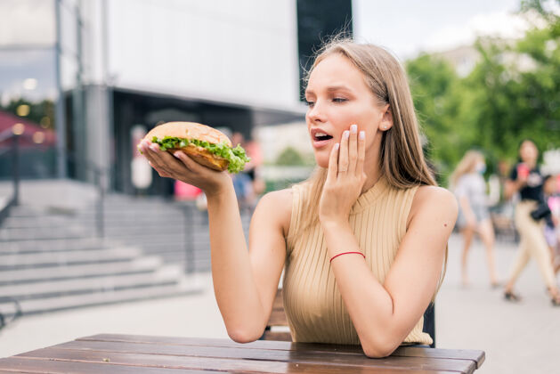 内美女在街上吃美味汉堡包的画像不健康饥饿膳食