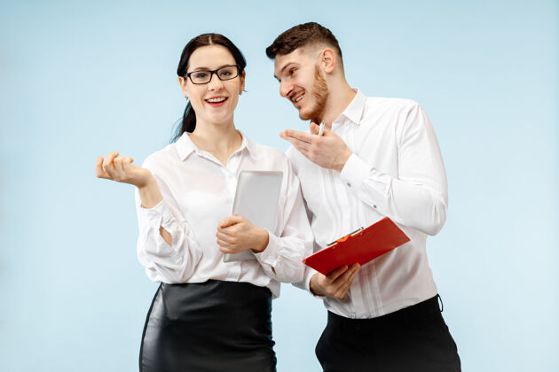 办公室商业伙伴关系的概念年轻快乐微笑的男女站在工作室蓝色背景下肖像微笑公司