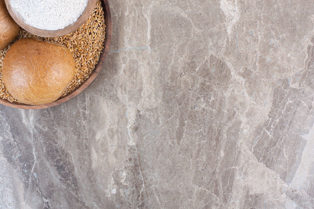 顶部视图两个小面包和一碗面粉放在大理石托盘上视图烘焙食品面团