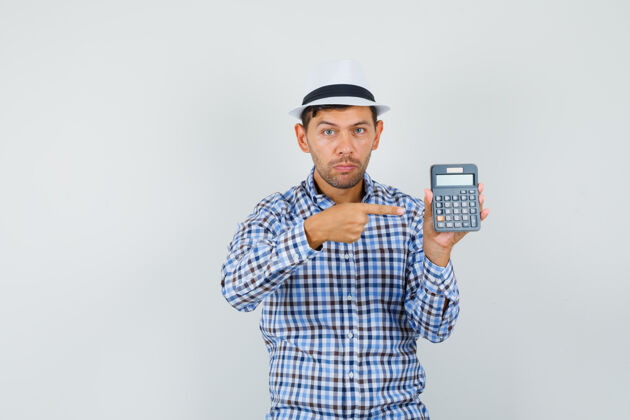 成年人穿着格子衬衫 戴着帽子的年轻人指着计算器 神情严肃男性肖像年轻
