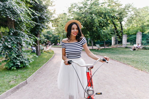 可爱美丽害羞的女孩漫步在绿色公园浪漫的黑发女士骑着自行车在户外消磨时光快乐欢笑户外