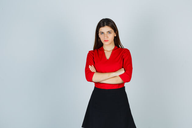 工作穿红衬衫 黑裙子的年轻女子双臂交叉站着 看上去很自信站立衬衫快乐