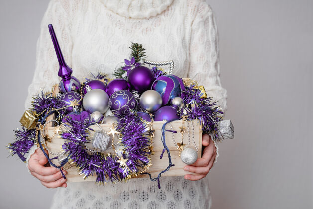 装饰女人手里拿着一个装满紫色圣诞装饰品的盒子礼物圣诞节传统