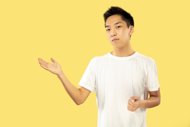 人韩国年轻人的肖像穿白衬衫的男模展示一些东西人类情感的概念 面部表情前视图流行的颜色帅气人手