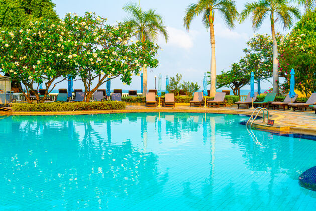 蓝色带椰子棕榈树的游泳池周围的椅子游泳池和雨伞-假日和度假概念美丽伞度假