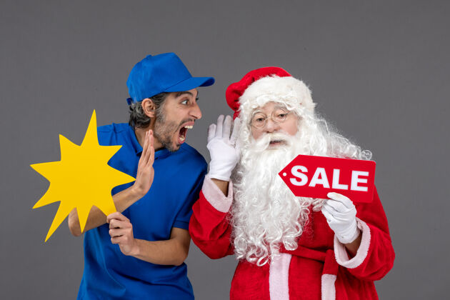 圣诞快乐圣诞老人与男性信使持有黄色标志和灰色墙上的销售横幅前视图人男人圣诞老人