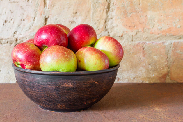 颜色新鲜的苹果放在砖墙背景的金属板上素食砖头苹果