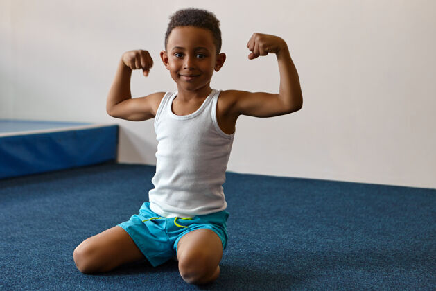童年快乐快乐的黑皮肤男孩的肖像 留着非洲短发在健身中心锻炼年轻肌肉身体
