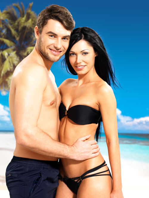 深色在热带海滩上 一对幸福微笑的相爱的美丽夫妇的画像季节海岸晒黑
