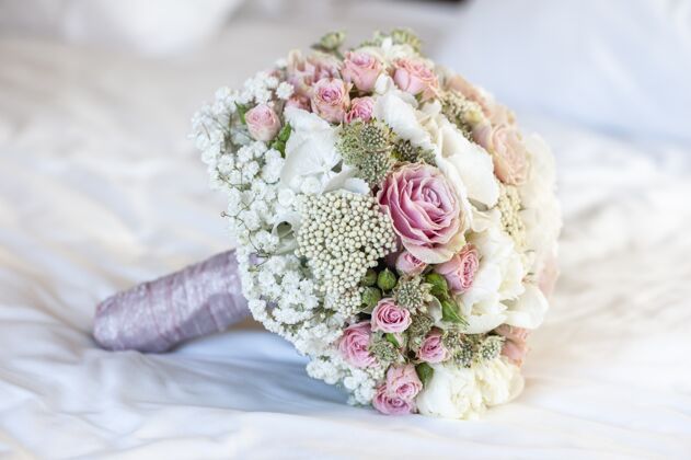 浪漫特写镜头的新娘花束上的白色床单与白色 粉红色和绿色的颜色花新娘玫瑰