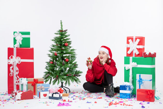 圣诞快乐前视图：年轻女子围坐在白色墙壁上拿着礼物抱着冬天快乐