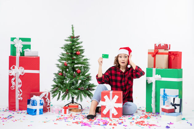 人正面图：年轻女子围坐在白色墙上 手里拿着绿色的银行卡礼物圣诞快乐冬天