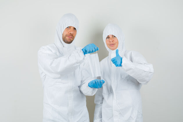 前面两个医生戴着医用口罩 穿着防护服竖起大拇指治疗防护病毒