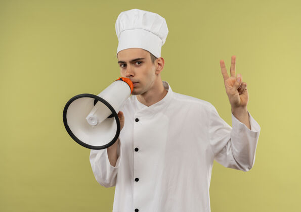 显示严格的年轻男厨师穿着厨师制服在扬声器上讲话显示和平的姿态厨师手势男