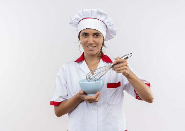 搅拌面带微笑的年轻女厨师穿着厨师制服拿着打蛋器和碗 有复印空间穿着厨师制服