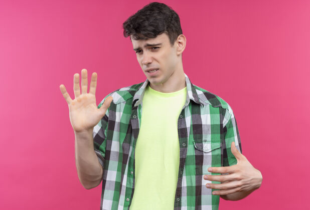 粉色一个穿着绿色衬衫 在孤立的粉色背景上做着停车手势的神经质白人年轻人穿着绿色男人