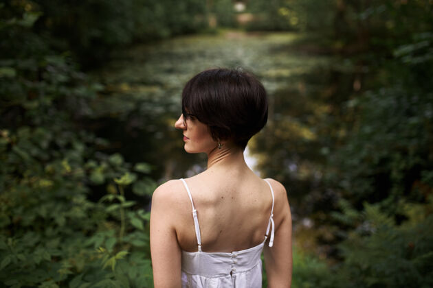 旅游在国家公园的池塘边 一位皮肤苍白 身材苗条 头发短发的年轻白种女人在户外放松的写真自然平静自由
