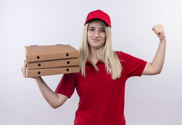 肩膀微笑着送礼物的年轻女孩穿着红色t恤 戴着帽子 肩上扛着披萨盒 在孤立的白色背景上做着强烈的手势微笑帽子抱着