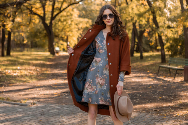 波西米亚迷人的时尚微笑的女人卷发漫步在公园穿着温暖的棕色外套秋季流行时尚 街头风格戴帽子和太阳镜服装夹克装束