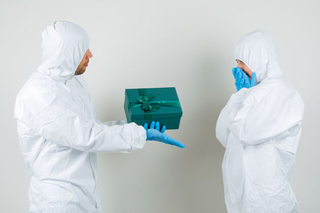 现代两个医生穿着防护服互相赠送礼品盒团队女人手