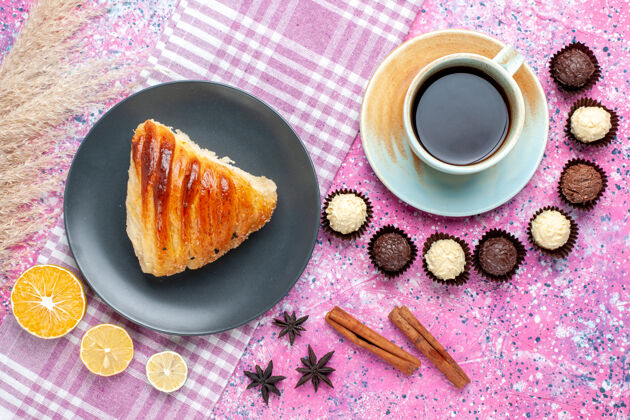 切片浅粉色表面上有一杯茶和巧克力糖果的糕点片俯视图盘子生的糖果