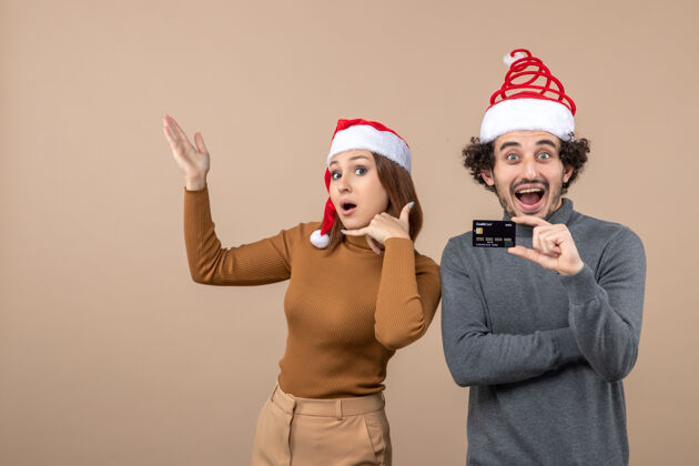 帽子圣诞节心情激动满意酷情侣戴着红色圣诞老人帽展示银行卡和女人打电话给我的手势人电话情侣
