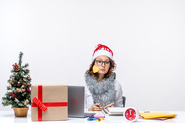 办公室前视图年轻的女工人坐在她的地方写笔记在白色的背景女士视图圣诞节