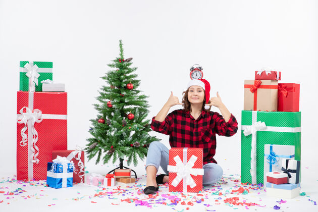 礼物一位年轻女子坐在一堵白墙上 头上拿着钟 围着礼物转礼物头人