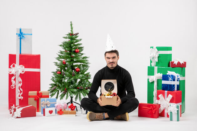 礼物年轻人围坐在白墙上的礼物面前快乐圣诞节人