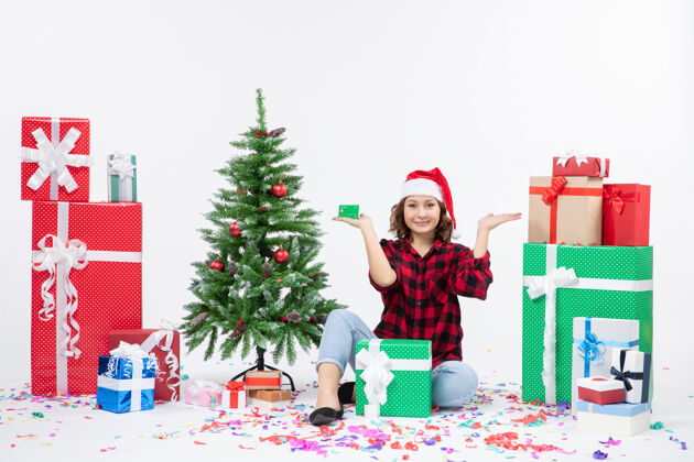 礼物正面图：年轻女子围坐在白墙上 手里拿着绿色的银行卡前面人圣诞快乐