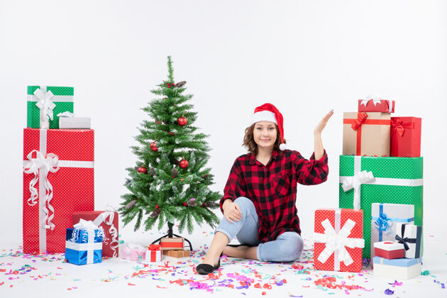 冬青年轻女子围坐在圣诞礼物和白色墙上的小圣诞树前的视图礼物礼物节日