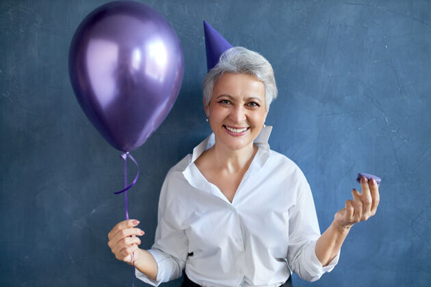 食物节日 庆祝和特殊场合的概念情绪有趣的高加索女性退休人员穿着节日服装手持氦气球画像乐趣女人吃