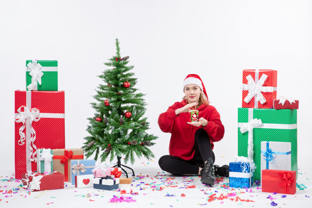 快乐前视图年轻女子围坐在一个白色的墙上拿着礼物庆祝圣诞坐着