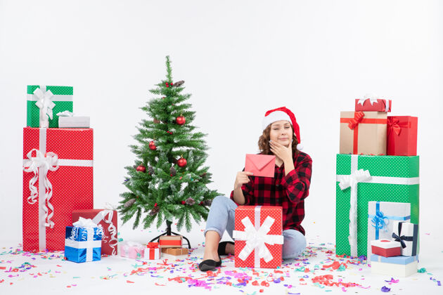人前视图年轻女子围坐在一个白色的墙上拿着信封的礼物圣诞情感树