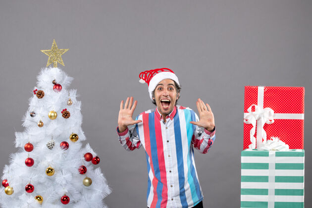 圣诞正面图快乐的男人张开双手站在白色圣诞树旁站立灰色打开