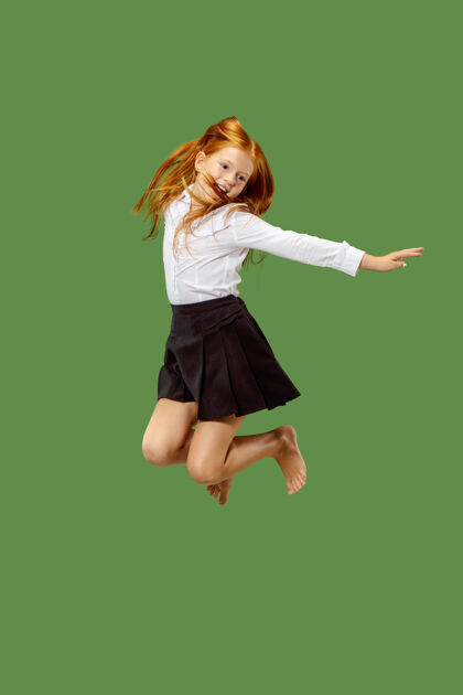 肖像年轻快乐的白人少女在空中跳跃 在绿色工作室背景上孤立美丽的女性半身像人类的情感 面部表情概念微笑跳跃休闲