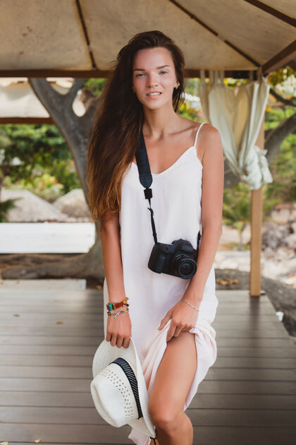热带年轻的自然美丽的女人穿着苍白的长袍在帐篷里摆姿势 热带度假 女性海滩春天