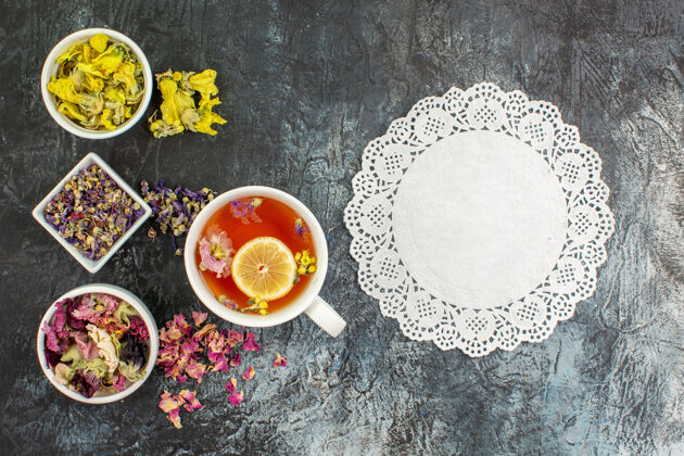 花边一杯凉茶的顶视图 灰色背景上有几碗干花和花边食物花顶
