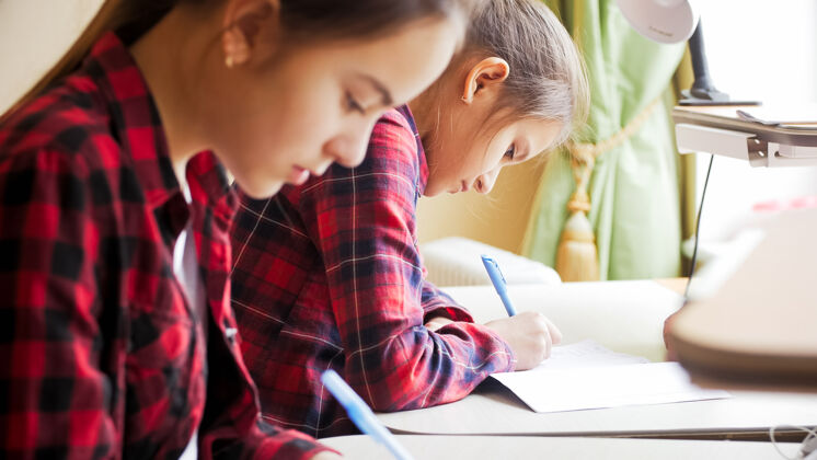 学习两个十几岁的女孩在家里做家庭作业绘画家庭作业书桌