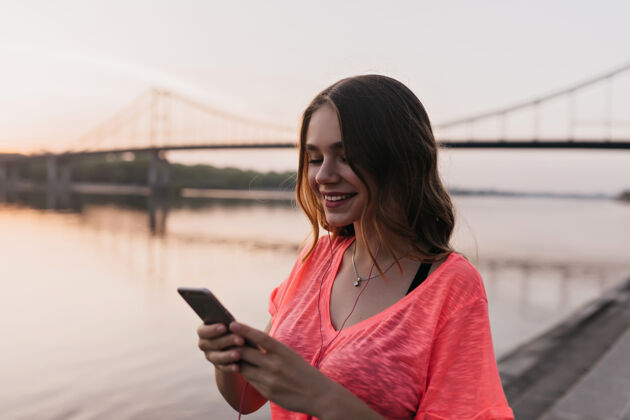 设备幸福的欧洲女人在河边用手机浪漫的女孩在湖边散步 发短信活动电话年轻