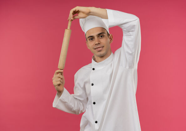 男面带微笑的年轻男厨师穿着厨师制服拿着擀面杖与复印空间厨师别针厨师
