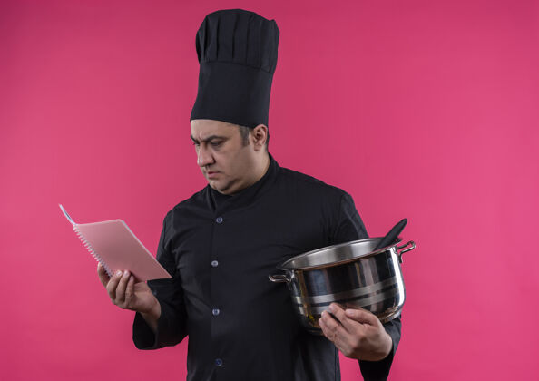 厨师想着中年男厨师穿着厨师制服拿着平底锅看着手里的笔记本手持中年男