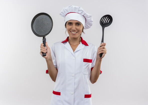 手拿面带微笑的年轻女厨师穿着厨师制服 手里拿着煎锅和抹刀 还有复印空间煎炸女穿